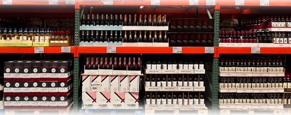 Wine bottles arranged in cartons across Costco warehouse shelving